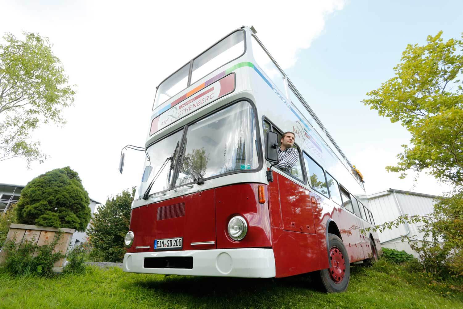 Roter Oldtimer Bus mit einem offenen Dach in der oberen Fahrgast-Ebene, ein Modell, das auch bei Stadtrundfahrten in Metropolen zum Einsatz kommt