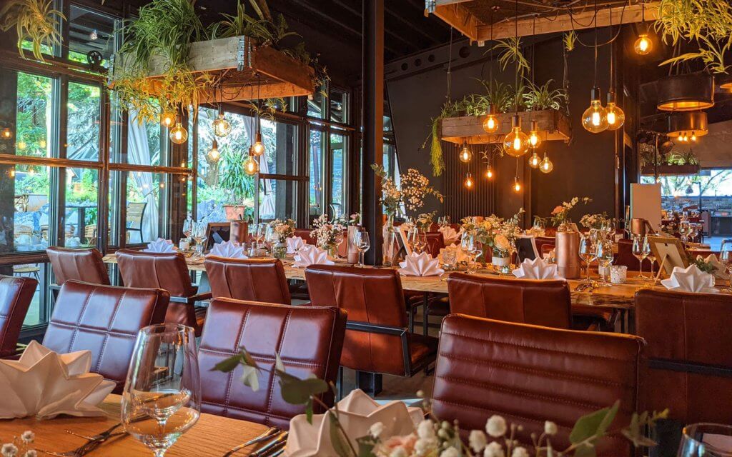 Restaurant mit gedeckten Tischen, von der Decke hängende Glühbirnen machen ein gemütliches Licht.